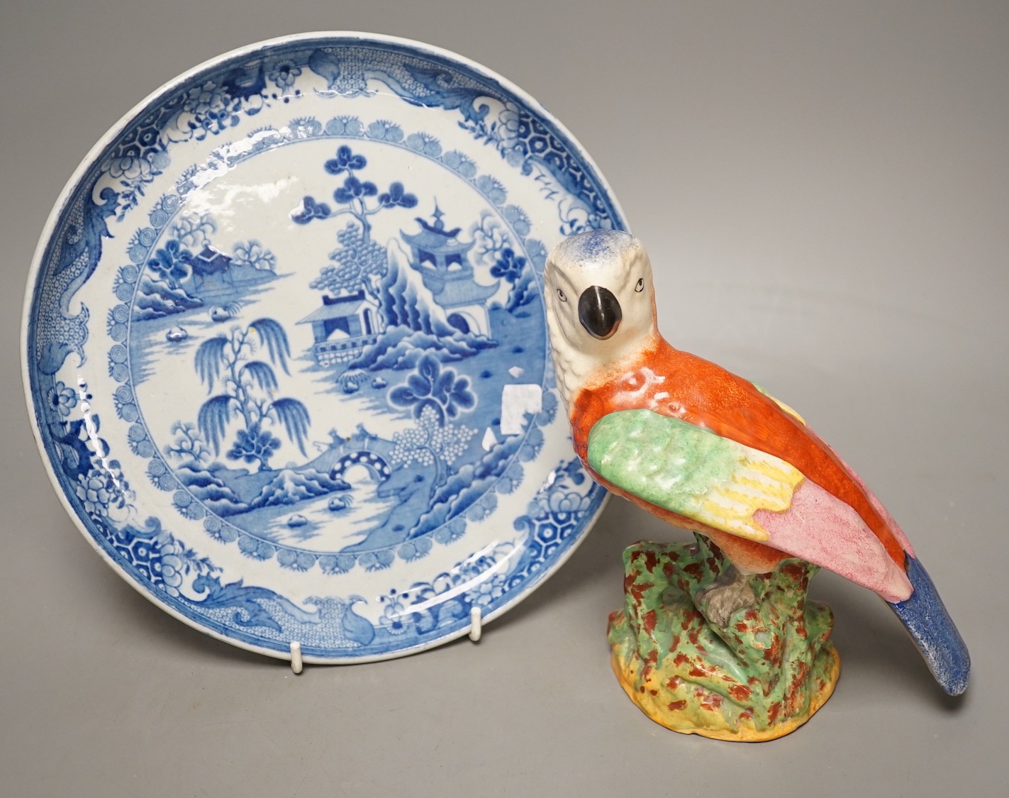 A Staffordshire pottery figure of a parrot, 19.5cm tall, together with a blue and white dish